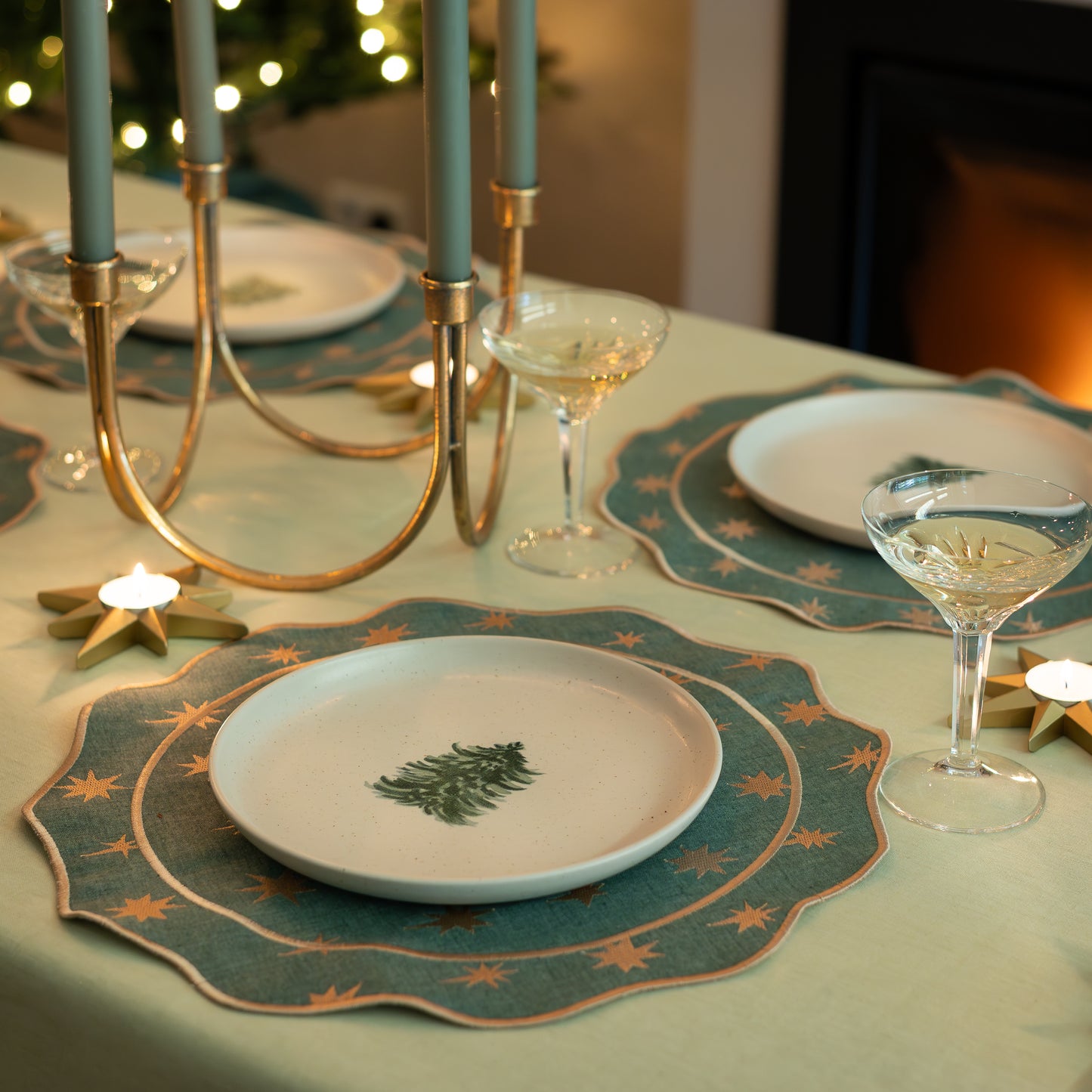 Sfeervolle kerst tafel lichtgroen met donkergroene placemats en kerstbordjes.