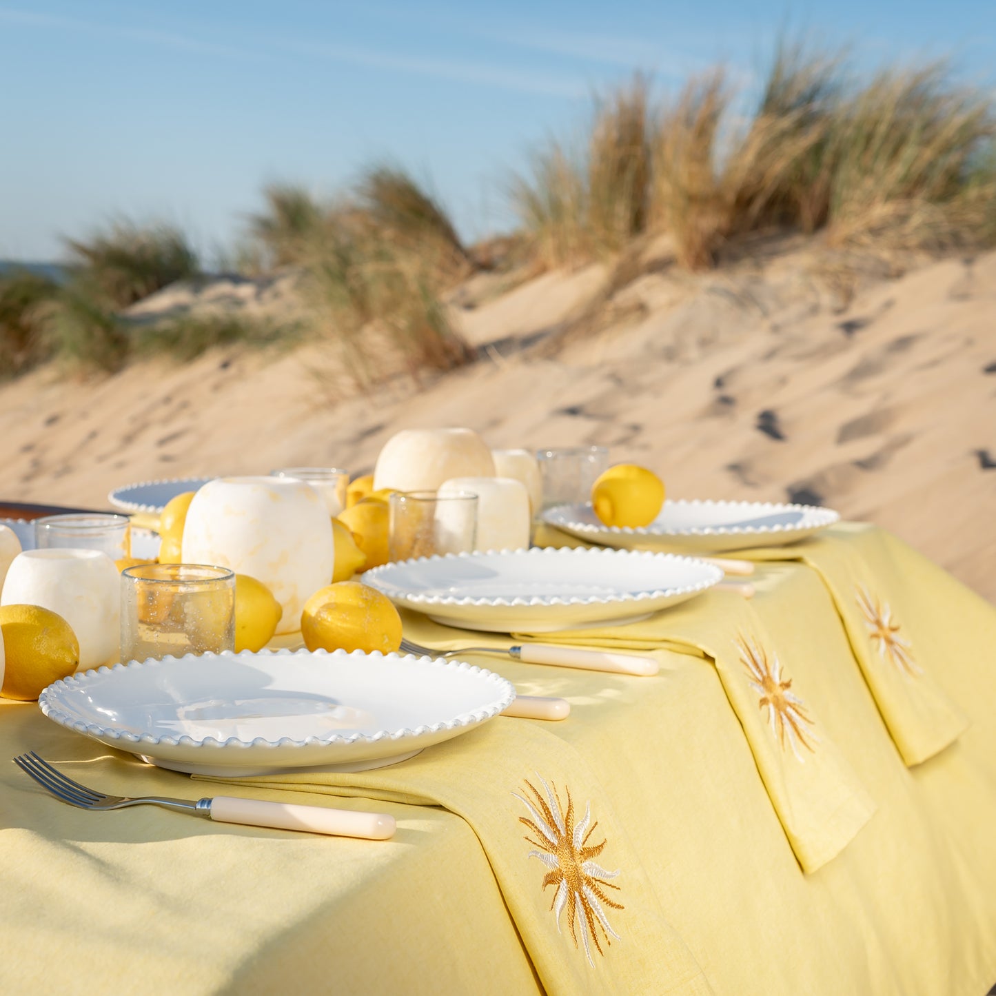 Botergeel tafelkleed met geborduurde servetten voorzien van zon en borden Pearl van Costa Nova