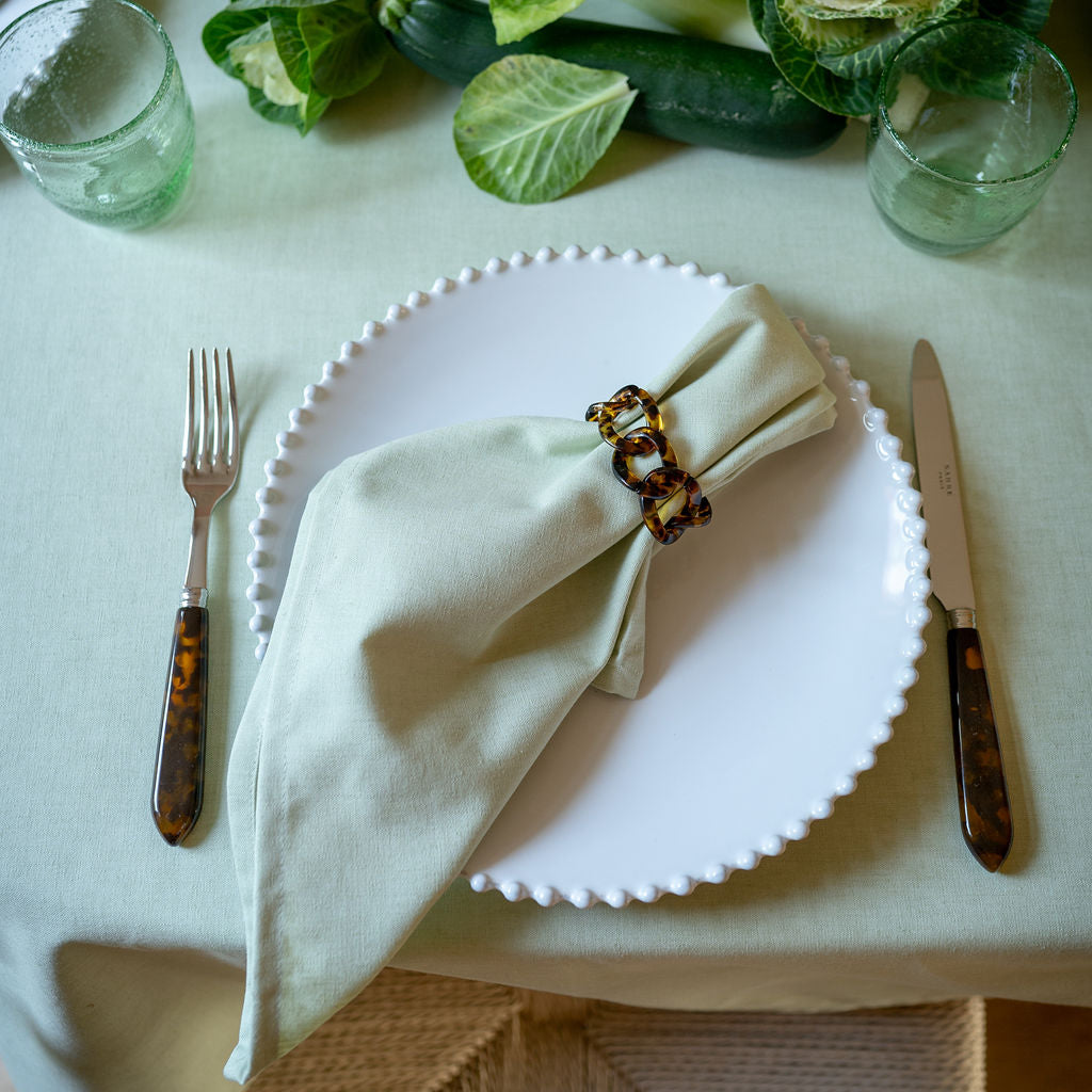 Lichtgroen tafelkleed en servet met servetring donkerbruin tortoise print en bestek tortoise. 