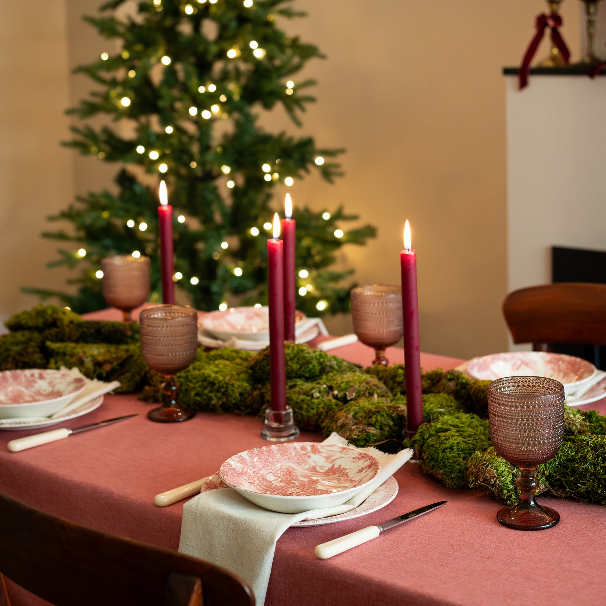 Kersttafel met stijlvol rood tafelkleed sfeerkaarsen in het mos